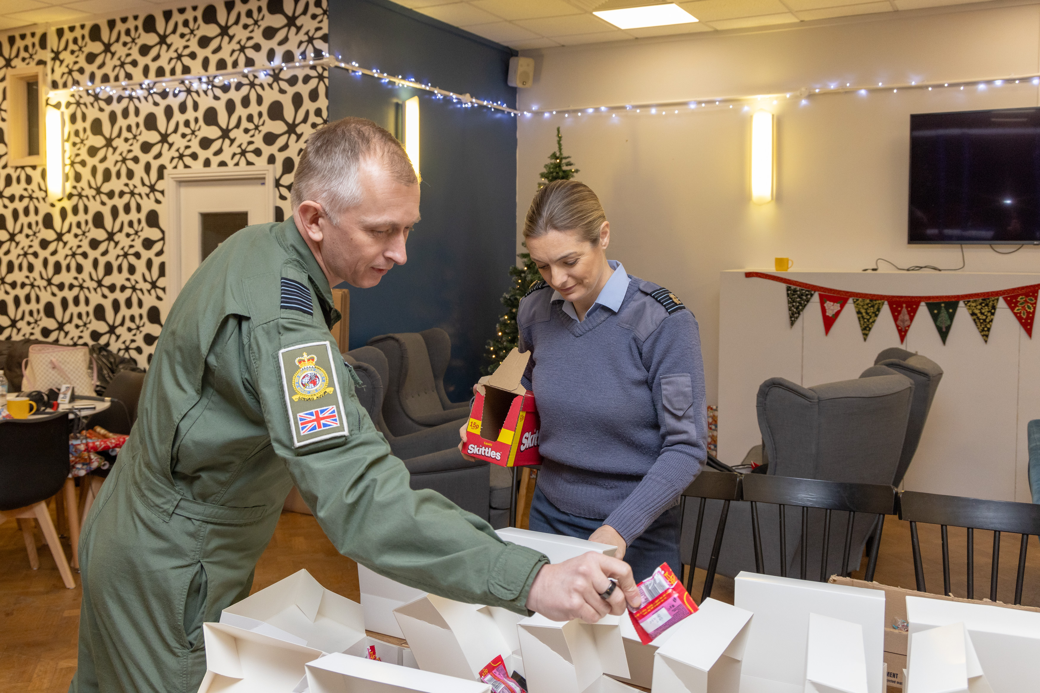 Photo - The Station Commander, Group Captain Claire O'Grady and Commander Air Wing, Group Captain Gareth Burdett, filling and wrapping Christmas boxes.